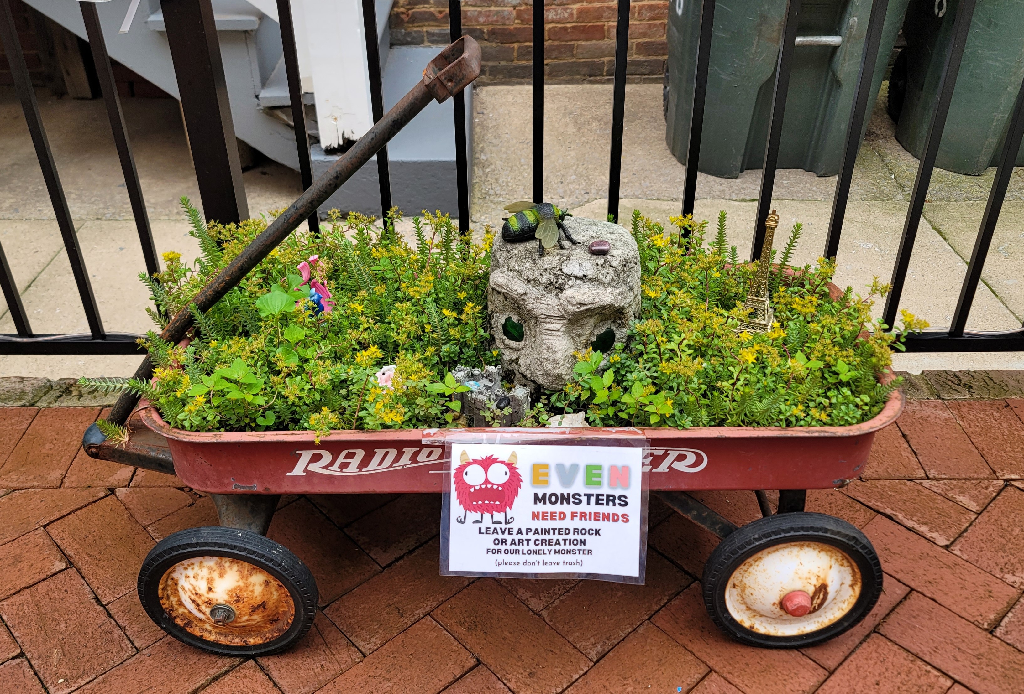 An old red Radio Flyer Wagon filled plants and a large rock. There is a sign that says 'Even Monsters Need Friends Leave a painted rock or art creation for our lovely monstrer (please don't leave trash).' I used to be carried around in a Radio Flyer wagon when I was very, very young and we lived in California. It's something my soul remembers, but my mind doesn't entirely. If something happens to me, I'll probably find myself back there. That's the feeling I get as I remember it.